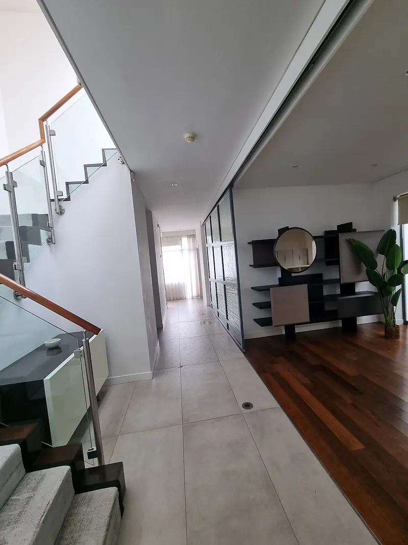 Bright, empty apartment hallway with a glass stair rail after clearance