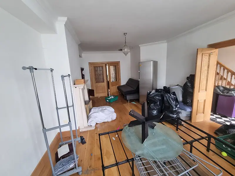 Apartment living room with bed frames, a clothes rail and bags gathered for removal