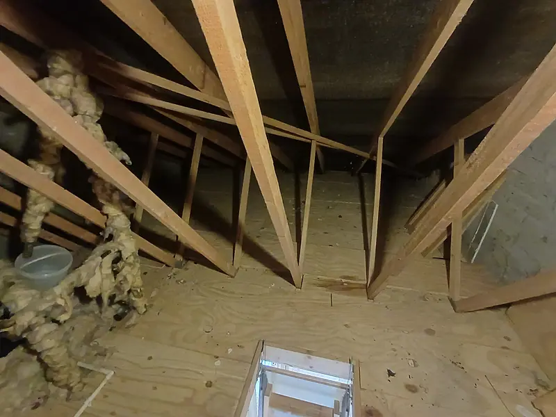 Cleared attic with a boarded floor between the roof trusses