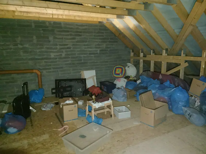 Boxes, bags and a child’s chair stored in an attic before clearance