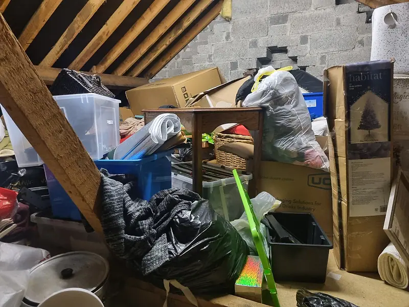 Attic floor stacked with boxes, bags and storage tubs under the roof timbers