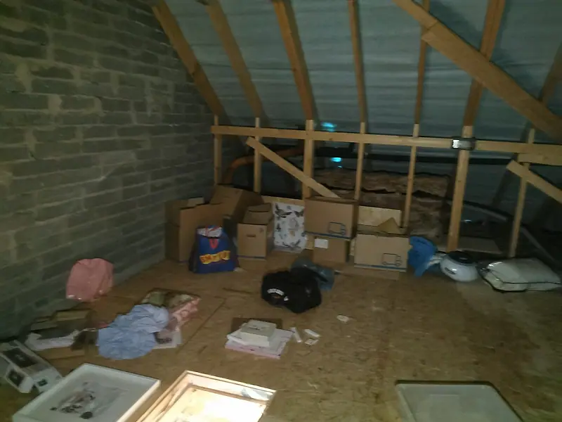 Stored boxes, bags and loose items spread across a loft floor