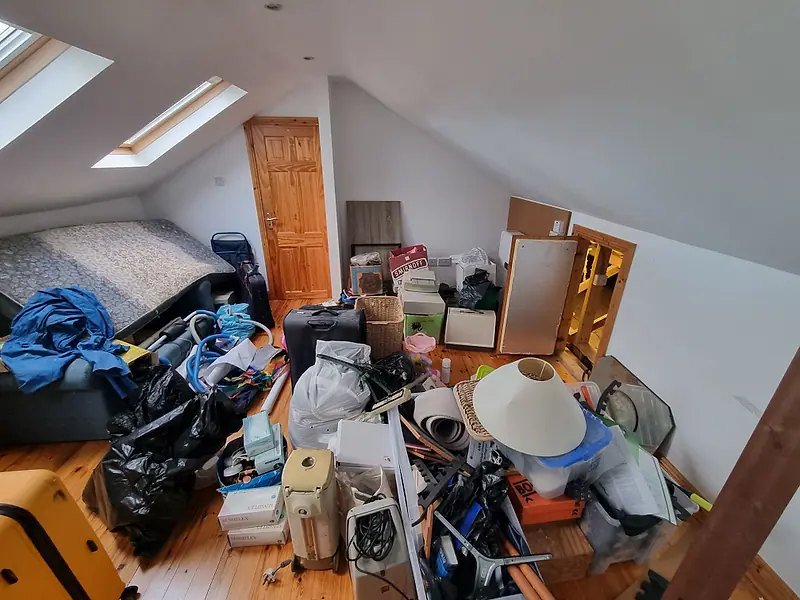 Converted attic room with roof windows, crowded with bags, boxes and household items