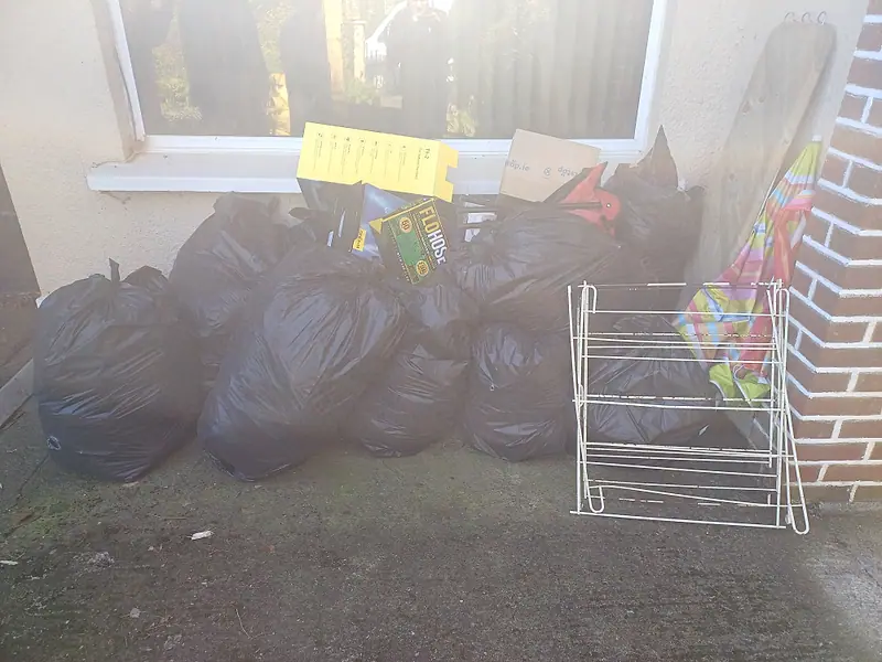 Black rubbish bags lined up under a window ready for collection