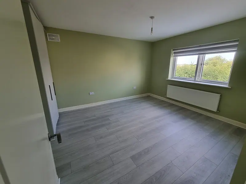 The same bedroom completely empty after the clearance, grey floor and green walls