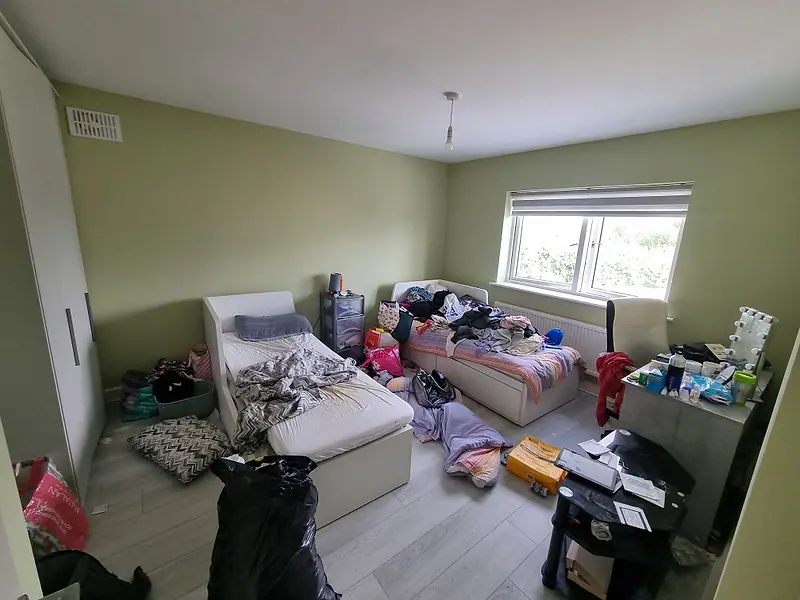 Bedroom with beds, bags and belongings across the floor before a house clearance