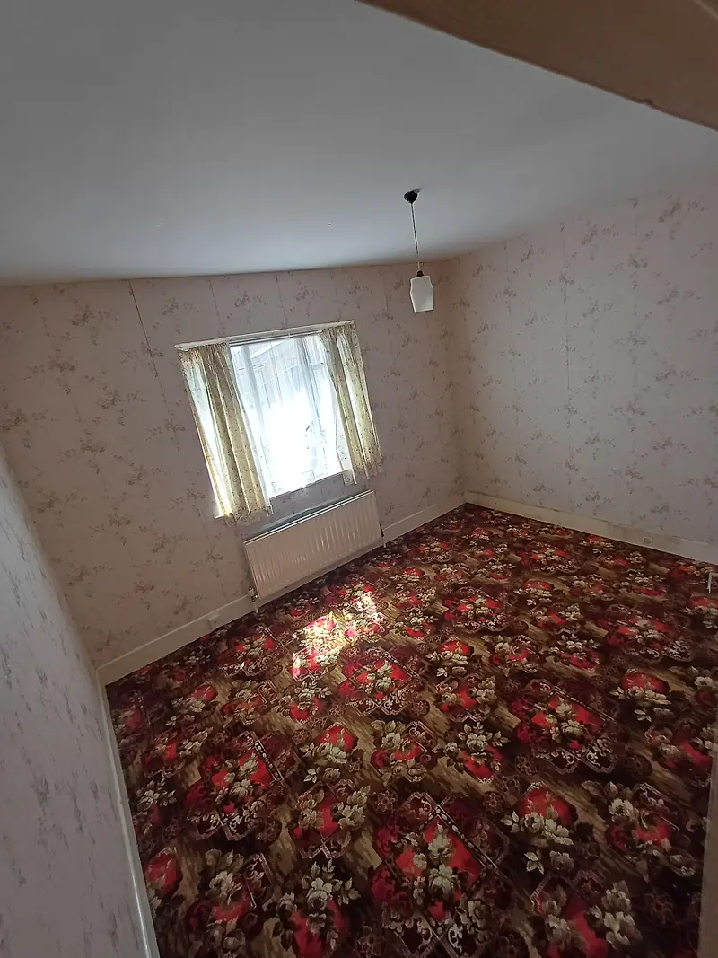 Empty bedroom with red floral carpet and sunlight through the window after clearance