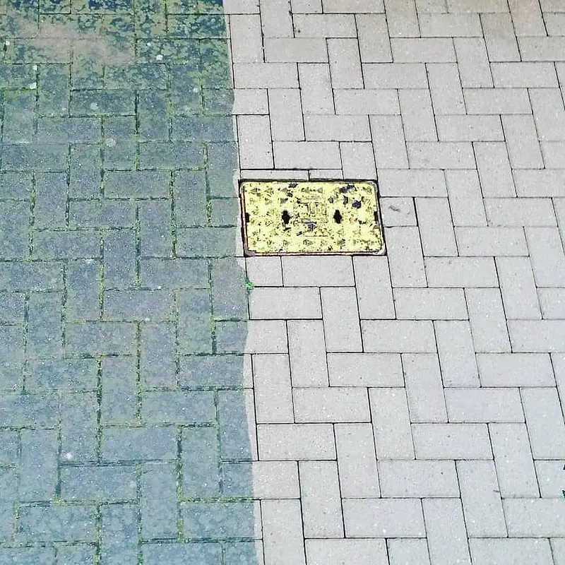 Grey block paving: the left half still green with moss, the right half washed clean