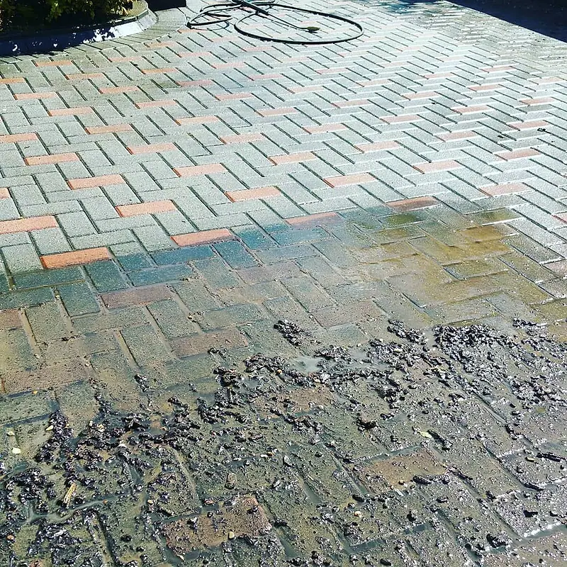 Moss and grime lifting off block paving during power washing