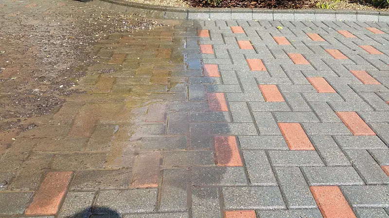 Red and grey block paving with the cleaned section beside the darker untreated paving