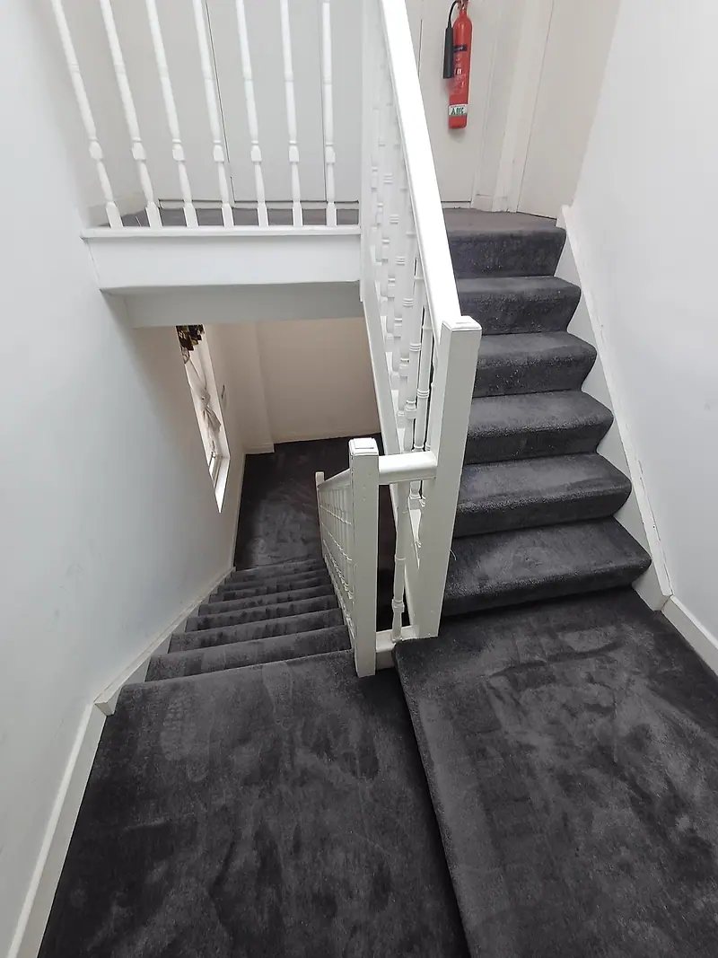 Communal stairs and landing with freshly cleaned dark grey carpet