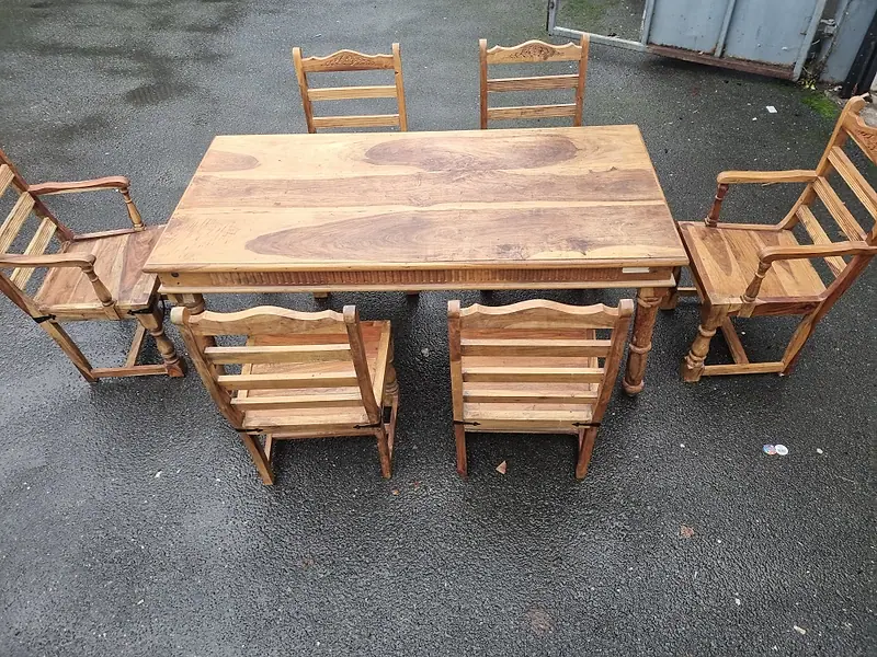 Solid wood dining table with six chairs set out for collection