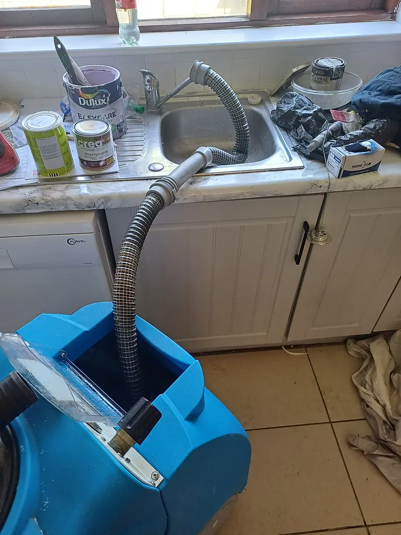 Portable carpet extraction machine draining its dirty water into a kitchen sink