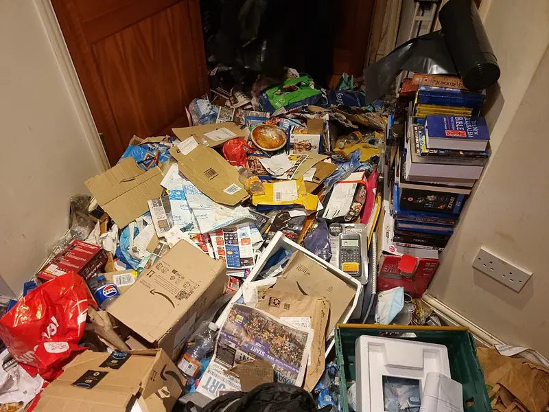 Floor covered in cardboard, packaging, books and household rubbish before removal