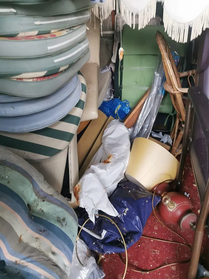 Garage packed with garden chairs, cushions, a lampshade and old furniture before clearance