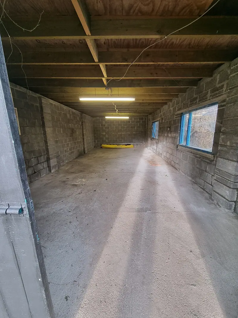 Long, empty garage with block walls and strip lighting after clearance