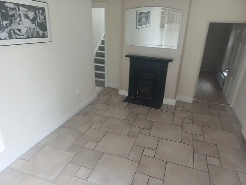 Empty hallway with a tiled floor and cast-iron fireplace after clearance