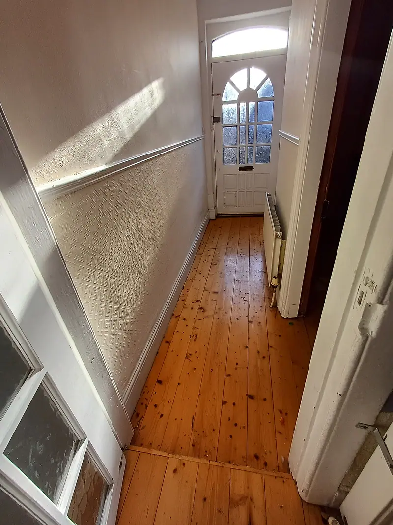 Bare pine-floored hallway after clearance