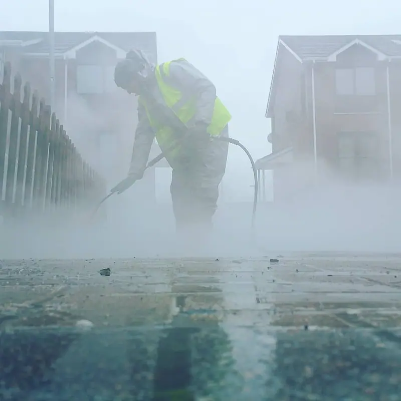 Hot-water pressure washing creating steam as it cleans paving outside a house