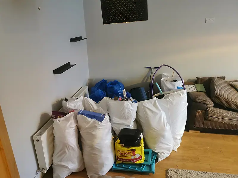 Bags of household items sorted and lined up in a room ready to load