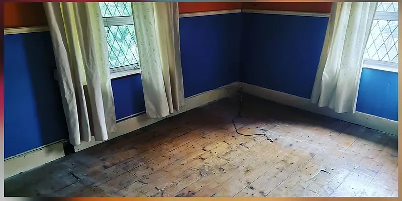 The same bedroom after clearance, floor clear under the blue walls and leaded windows