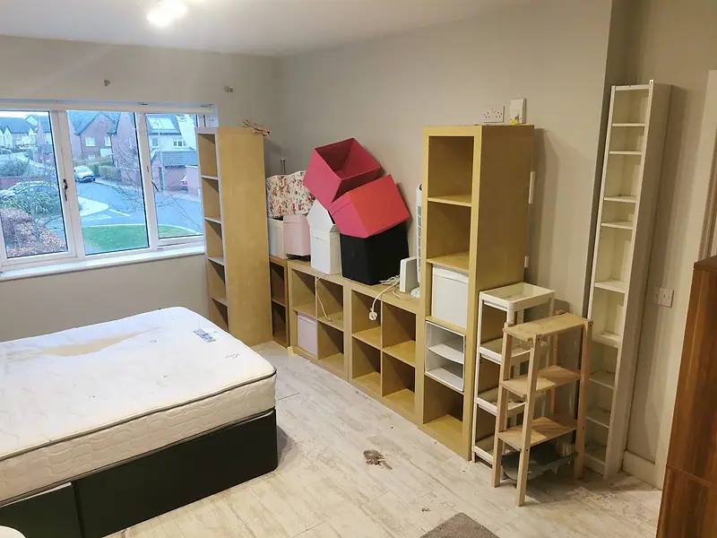 Bedroom with shelving units, storage boxes and a mattress ready to be removed