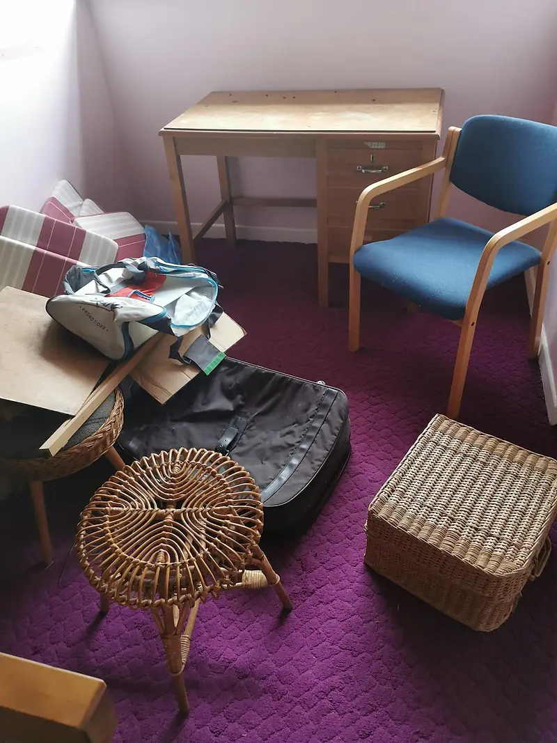 Dining chairs, a footstool, a basket and bags gathered for removal on a red carpet