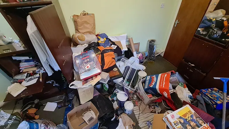 Small bedroom full of household items and bags before a house clearance
