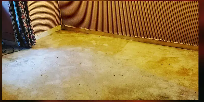 The same living room after clearance, furniture and carpet gone and the floor bare