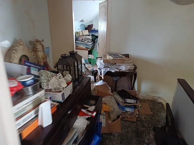 Living room with boxes, papers and ornaments covering the furniture before clearance