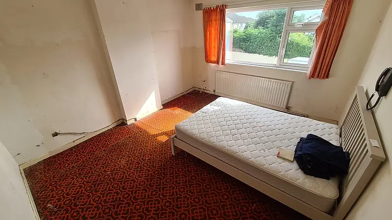 The Sutton front bedroom after clearance, the floor clear and only a bed left in the room