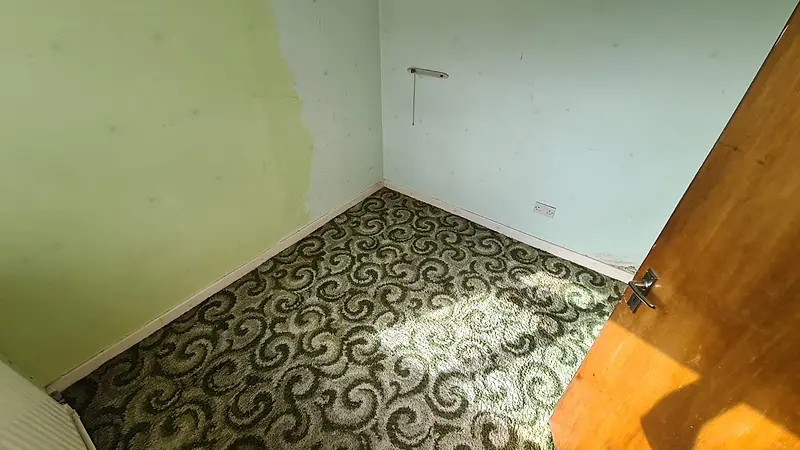 The same Sutton box room after clearance, completely empty with the patterned carpet showing