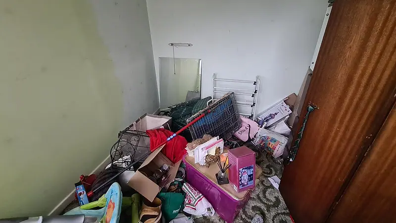 Box room in a Sutton house before clearance, the floor covered with boxes, clothes and household items