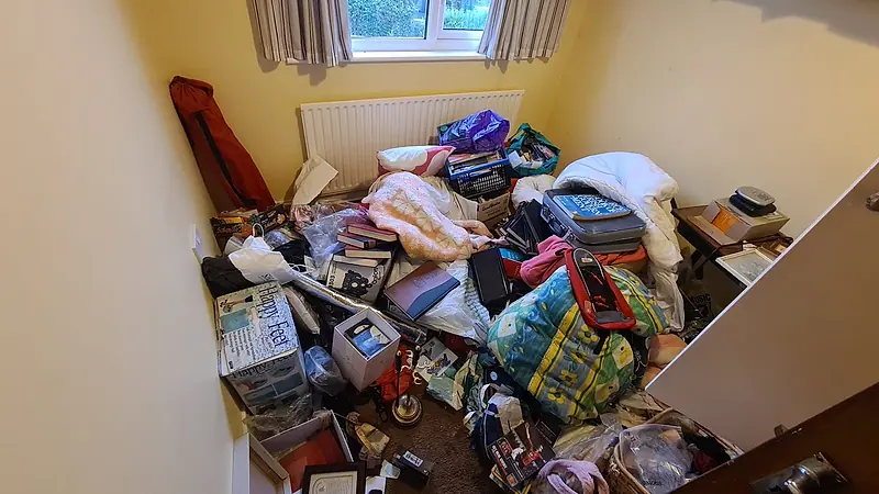 Bedroom floor in Sutton covered with bags, books and boxes waiting to be cleared