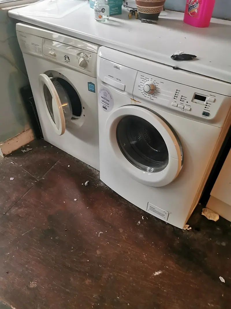 Two old washing machines waiting to be taken away for appliance recycling