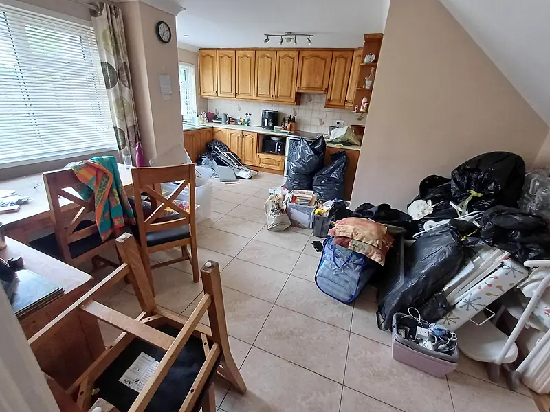 Kitchen-diner with bags, boxes and furniture piled up for clearance