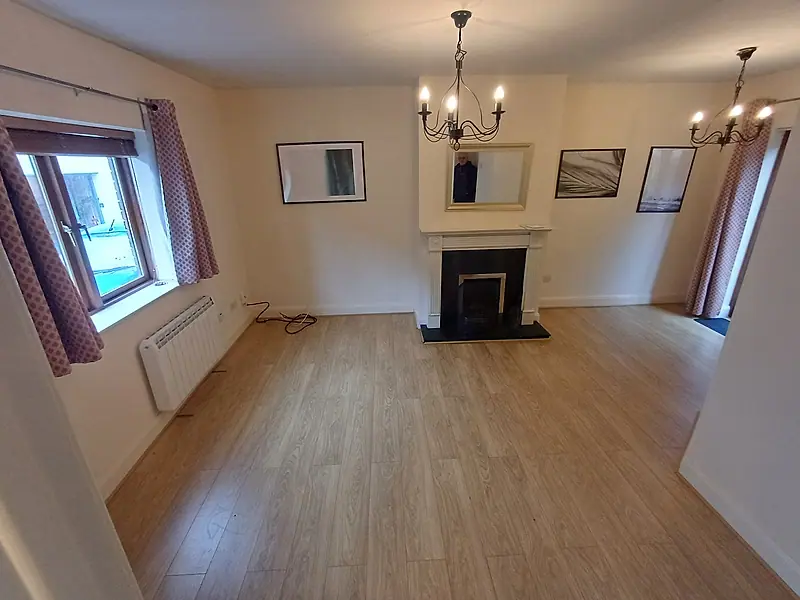 Empty living room with a laminate floor, fireplace and chandeliers after clearance