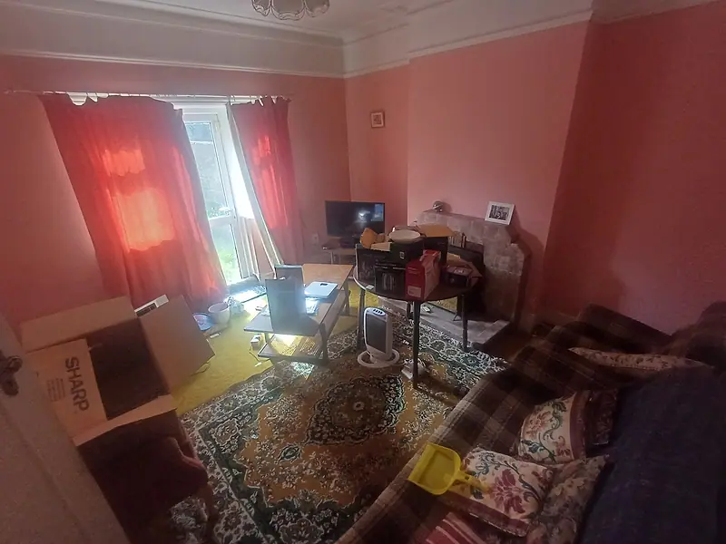 Living room with cluttered furniture and boxes before clearance