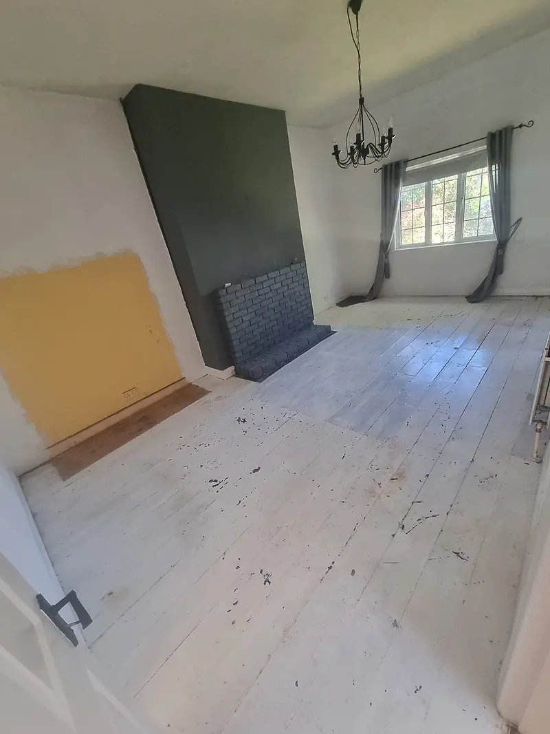 Empty living room with painted floorboards and fireplace after a clearance