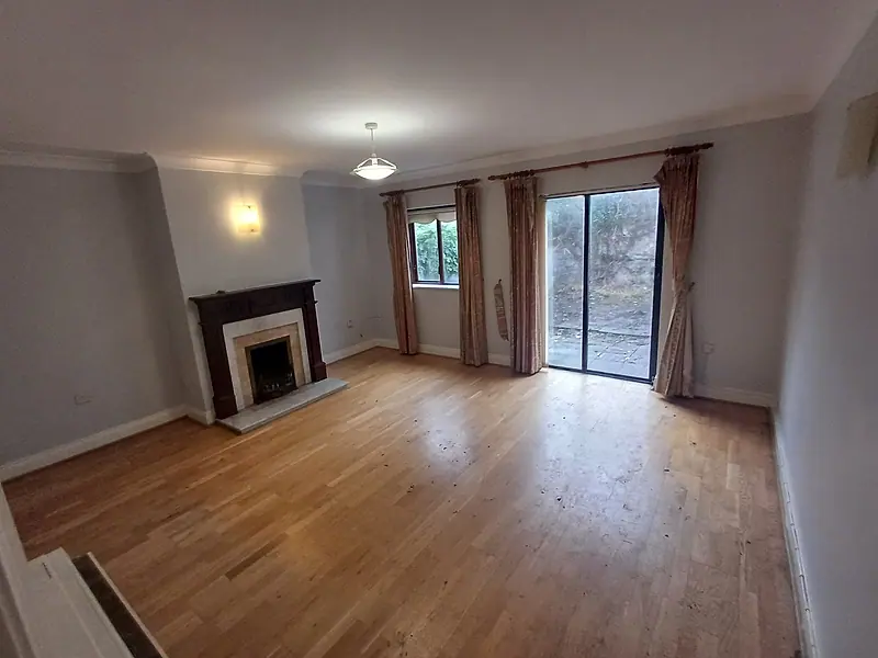 Empty living room with a wooden floor, fireplace and patio doors after clearance