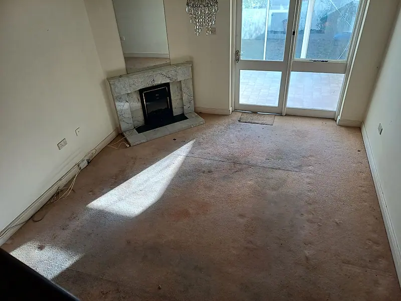 The same living room completely cleared, with the marble fireplace and patio doors showing