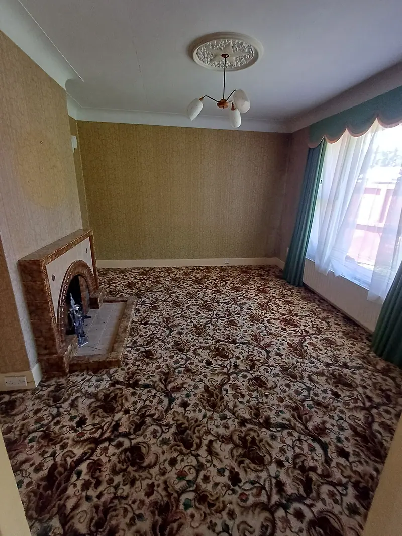 Cleared living room with patterned carpet and a tiled fireplace