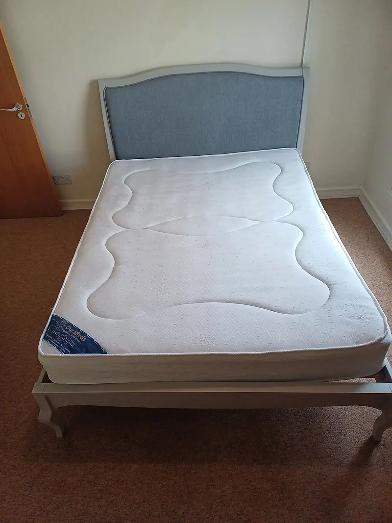 Double mattress on a grey upholstered bed frame after cleaning
