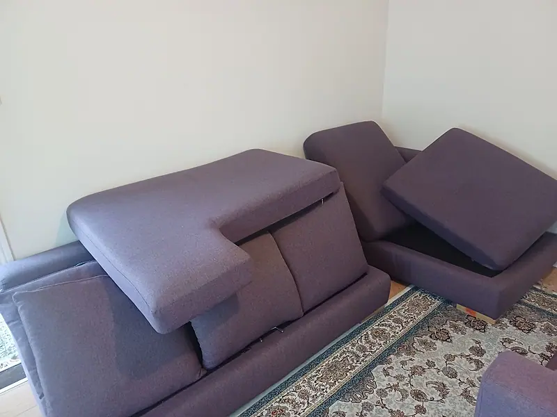 Purple modular corner sofa with cushions lifted during cleaning