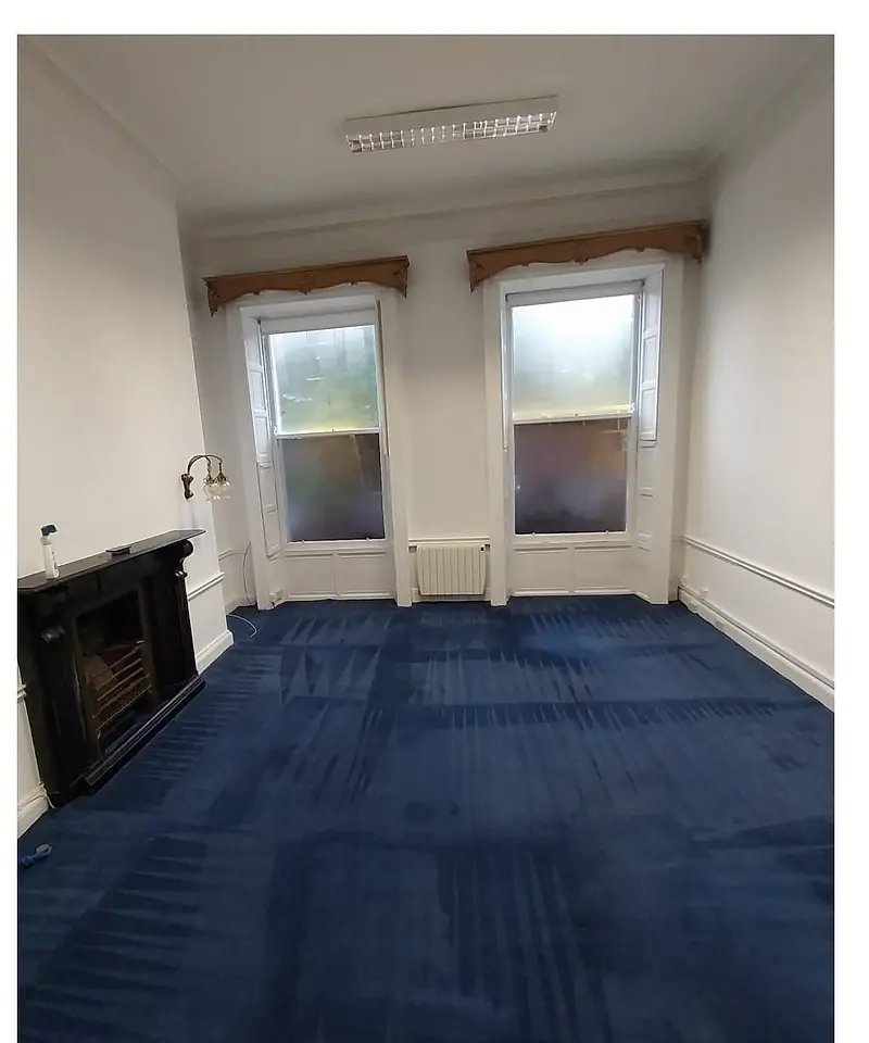 The same office after clearance, empty with the blue carpet tiles showing