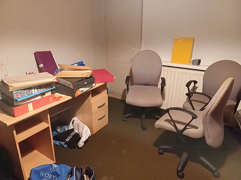 Home office with a desk, files and chairs awaiting clearance