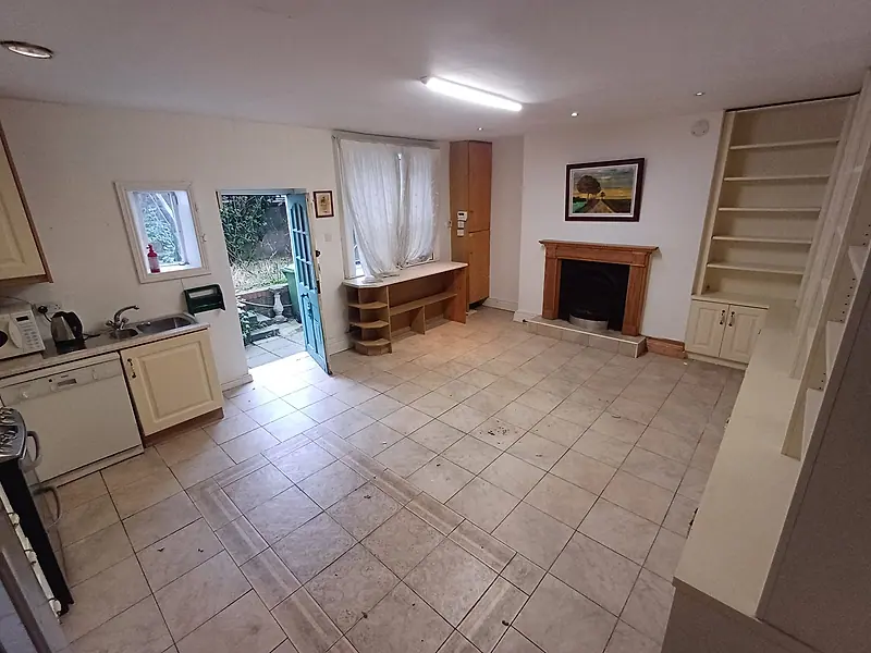 Cleared open-plan kitchen and living area with a tiled floor and fireplace