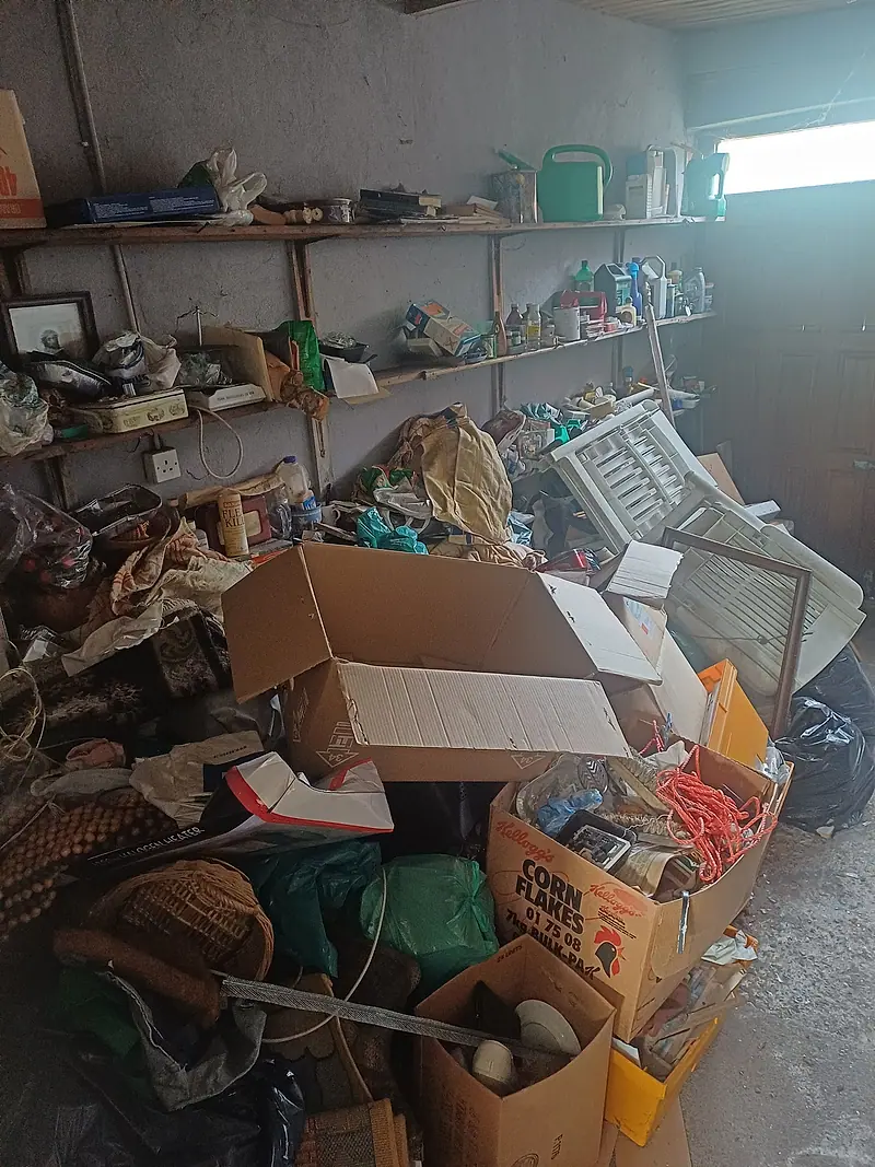 Outbuilding shelving and floor heaped with boxes and household items