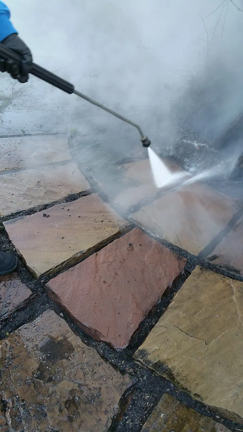 Sandstone patio slabs being cleaned with a high-pressure spray