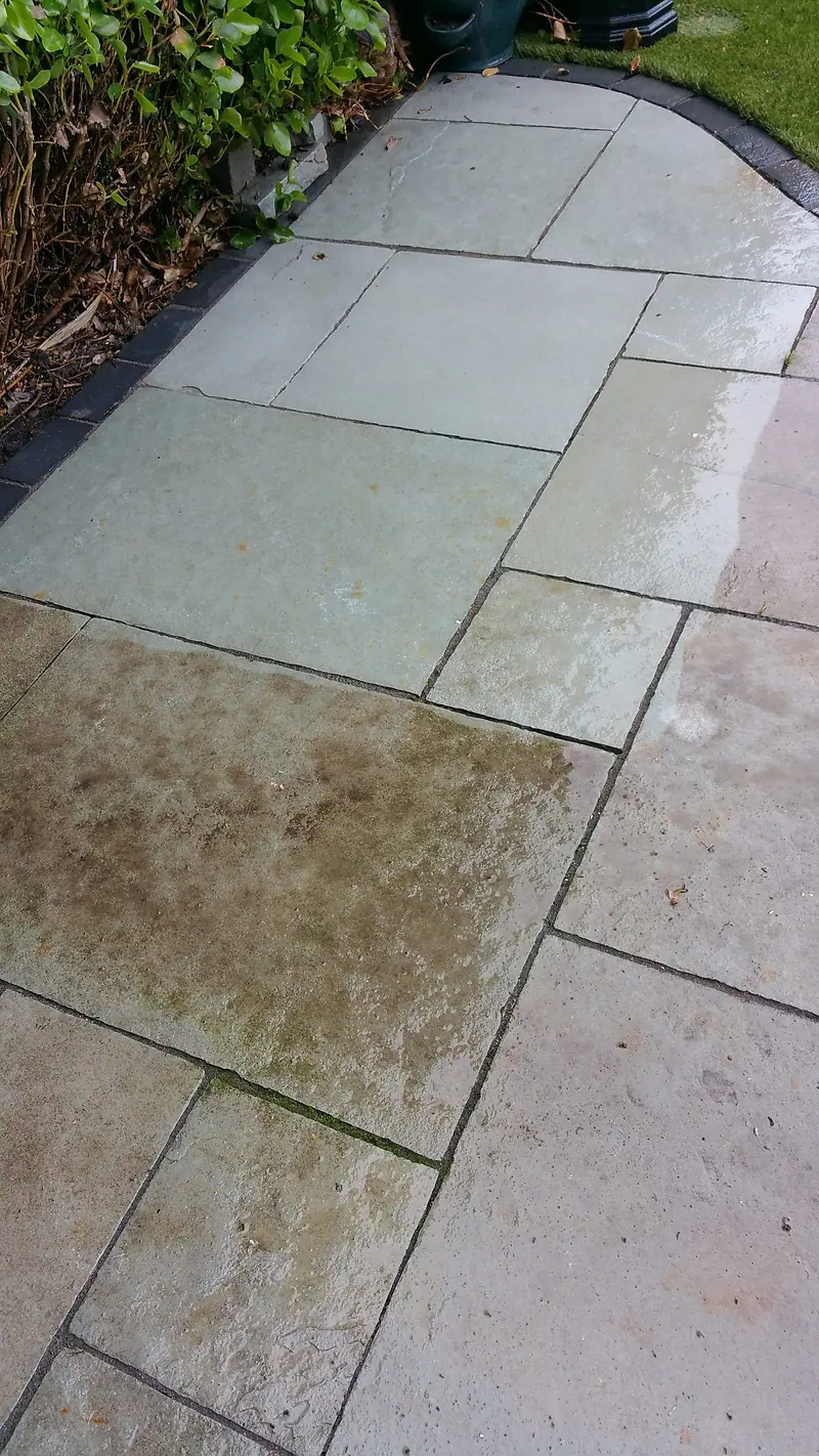 Patio slabs part-cleaned, the washed slabs pale against the dark untreated ones